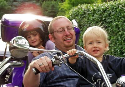 Vater mit Kindern auf stehendem Motorrad