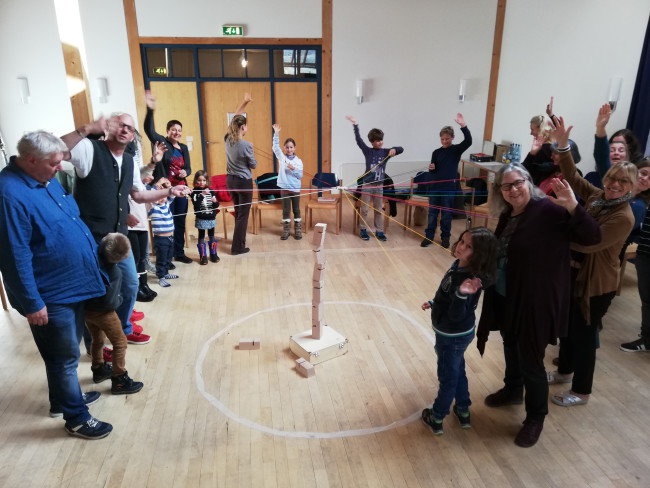 Kinder und Erwachsene bilden Kreis, alle sind mit einem Faden miteinander verbunden